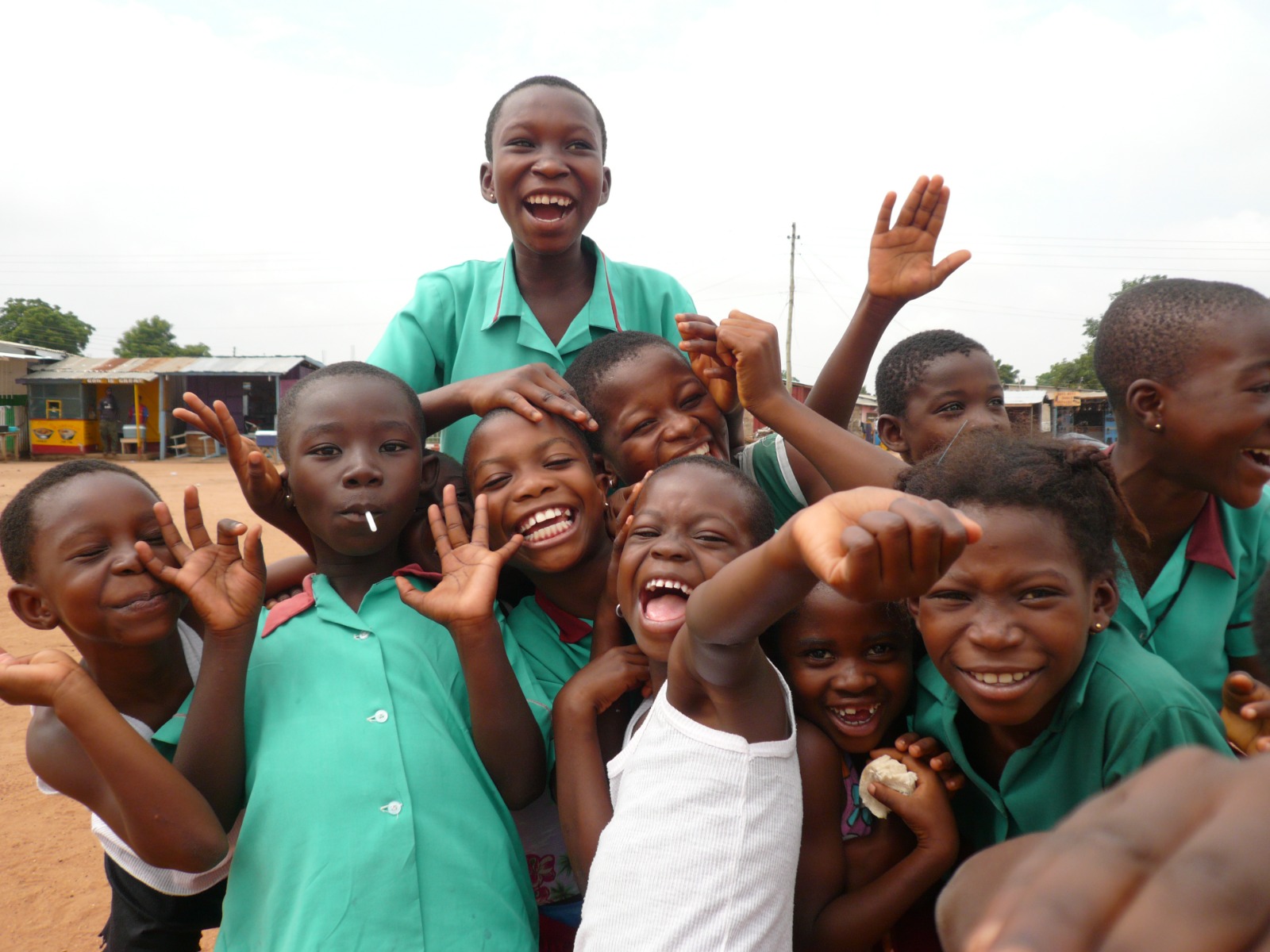 Children laughing and waving together in a Ghanaian community