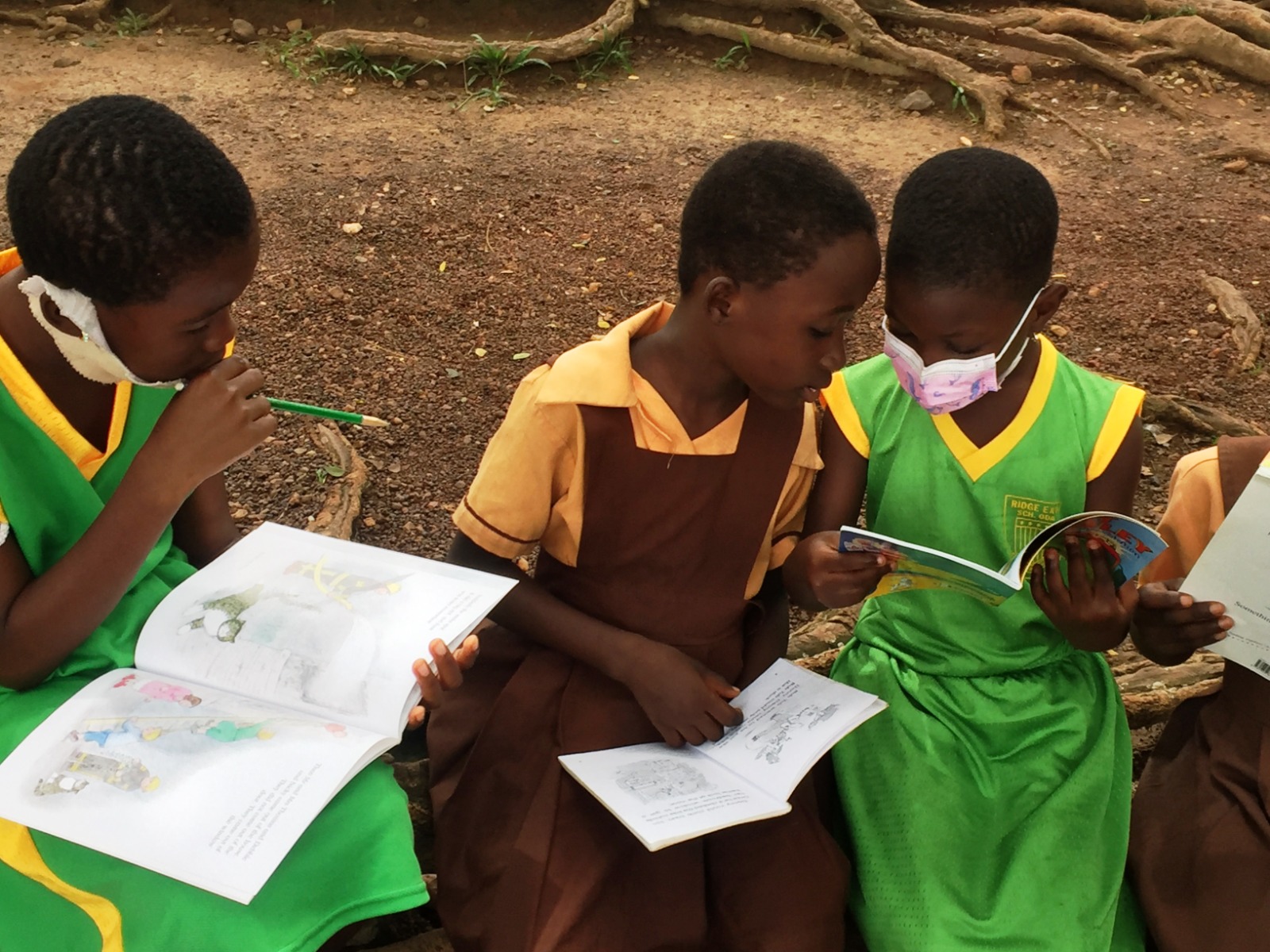 Children reading books together under a tree